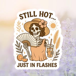 May include: A sticker featuring a skeleton wearing a hat and holding a fan and a drink. The text on the sticker reads "STILL HOT... JUST IN FLASHES". The design includes orange slices, a sun, and floral elements.
