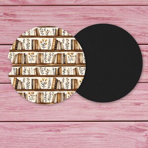 May include: Two car coasters. One coaster features a watercolor design of a bookshelf with books and floral accents. The other coaster is solid black. The coasters are round with a small notch for easy removal.