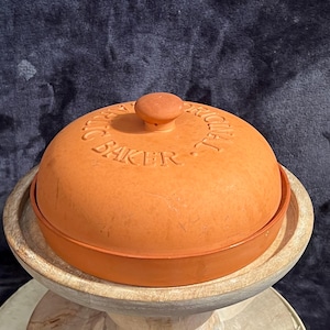 May include: A terracotta dome-shaped bread baker with the text "Original French Baker" embossed on the top.