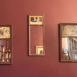 May include: Three framed mirrors with different images inside. The mirror on the left has a picture of a hunting scene with horses and riders. The mirror in the middle has a picture of two dogs. The mirror on the right has a picture of a group of people in a room.