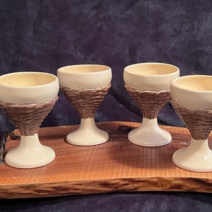 May include: Four ceramic goblets with a brown and white design. The goblets are sitting on a wooden tray.