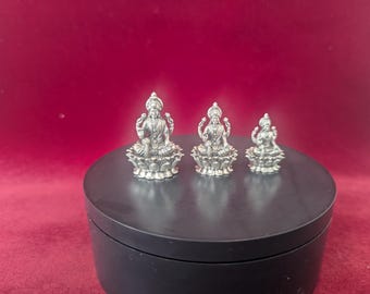 Peut inclure: Trois figurines en argent de la déesse hindoue Lakshmi assises sur des bases de fleurs de lotus. Les figurines sont de tailles différentes, la plus grande étant au centre.