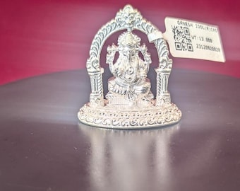 Peut inclure: Statuette en argent de Ganesha avec des détails complexes, assis sur un trône avec une arche au-dessus. L'idole est sur une surface noire. L'étiquette indique "GANESH IDOL (ICAS) WT: 13.000 23120920028"