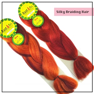 May include: Two packs of pre-braided hair extensions in red and orange ombre colors. The packaging features the brand name "Rast Afri" and the text "New afrelle". Silky Braiding Hair.