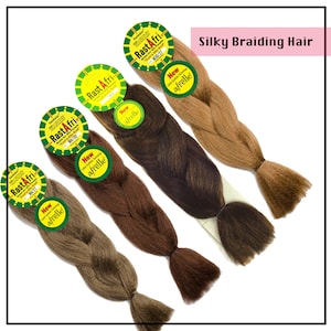 May include: Four bundles of Silky Braiding Hair in shades of brown and blonde. Each bundle has a tag that reads "RastAfri" and "afrelle". The text "Silky Braiding Hair" is in a pink box in the upper right corner.