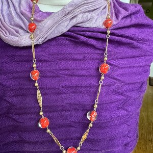 Gold tone necklace with red &#39;marble&#39; glass beads.
