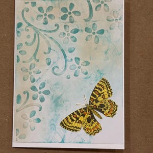 Puede incluir: Tarjeta de felicitación hecha a mano con un diseño de mariposa. La tarjeta presenta un patrón floral turquesa y una mariposa amarilla, negra y naranja. Las palabras "Style #2" están impresas en la parte superior.
