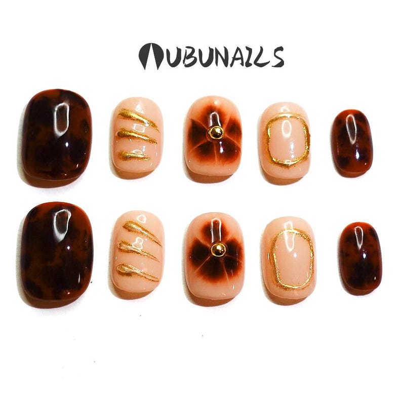 Short almond-shaped handmade press-on nails in ombre brown and peach gold tones. 3D gel design features free-style sculpted flowers, giving a delicate and elegant look. The nails have a clean, simple finish, perfect for daily wear or special occasions like birthday partiy. Subtle shimmer adds a festive touch, making them an ideal gift for her. Displayed neatly in a set, highlighting the smooth glossy texture and intricate floral details. Suitable for OOTD styling or gifting as a birthday present