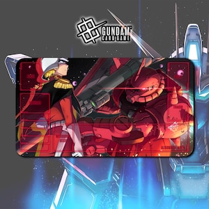 Peut inclure: Tapis de jeu de cartes Gundam rectangulaire avec une illustration rouge et noire d'un personnage Gundam et d'un robot rouge. Le tapis de jeu comporte des zones étiquetées pour les cartes et le logo Gundam Card Game.