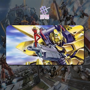 Op de afbeelding: Een rechthoekige Gundam-kaartspelmat met een gele en paarse mech die een groot geweer vasthoudt, met een persoon in een rood pak erop. De achtergrond toont andere mechs en een stadsgezicht. Het Gundam-kaartspellogo staat in het midden bovenaan.