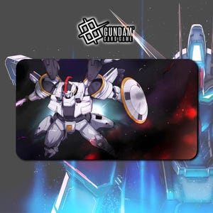 May include: A rectangular Gundam card game playmat featuring a white and grey robot with a red crest, holding a shield. The background depicts a space scene with red and purple nebulas. The Gundam Card Game logo is in the top left corner.
