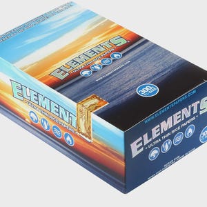 May include: A box of Elements ultra-thin rice papers. The box features a gradient design of blue, orange, and yellow, with the brand name and product details in white and green. The box contains 300 papers.