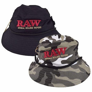 May include: Two bucket hats. One is black with red embroidered text that reads "RAW NATURAL ROLLING PAPERS". The other hat has a camouflage pattern with the same red embroidered text. Both hats have a black rope detail around the brim.