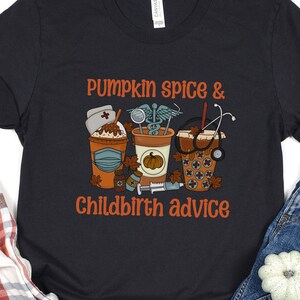 May include: Black t-shirt with the text "Pumpkin Spice & Childbirth Advice" in orange. The graphic features three coffee cups with medical-themed designs, including a nurse's hat, stethoscope, and syringe. A plaid shirt and jeans are also in the image.