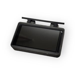 Puede incluir: Una pantalla rectangular negra con un marco negro y un soporte de montaje negro. La pantalla está montada en el soporte con dos tornillos.