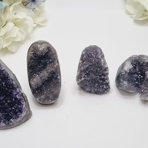 May include: Six amethyst crystal geodes of varying sizes and shapes. The crystals are a deep purple colour and have a natural, rough texture.