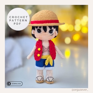 Könnte beinhalten: Gehäkelte Puppe einer Figur mit Strohhut und rotem Band, roter Weste mit gelben Knöpfen, blauen Shorts und gelbem Schärpe. Die Puppe hat schwarzes Haar und ein lächelndes Gesicht. Der Text "CROCHET PATTERN PDF" und "DOWNLOAD" ist enthalten.
