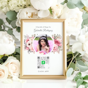 May include: A white card with a gold frame, featuring a floral design and a photo of a young woman. The text "A Sprinkle of Magic for Gabriella Rodriguez" is printed at the top. A QR code with the text "CASH APP" is printed below the photo.