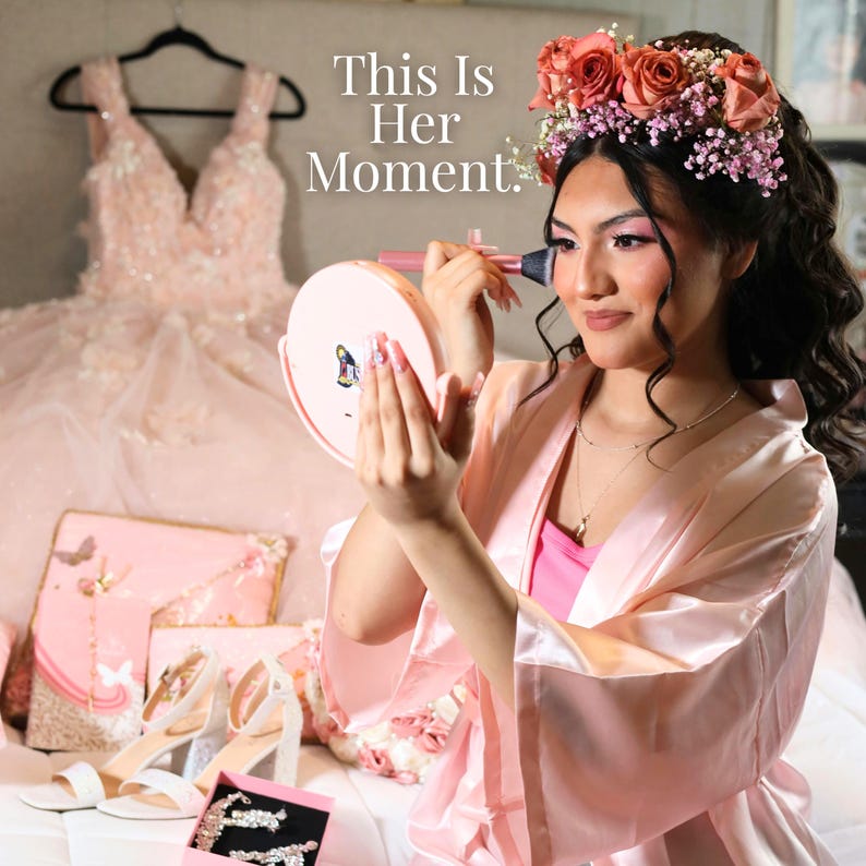 K&ouml;nnte beinhalten: Ein hellrosa Satin-Kimono, ein Blumenschmuck und ein Kleid sind in diesem Bild zu sehen. Der Text "This Is Her Moment" ist sichtbar. Weitere Artikel sind ein Schminkspiegel, High Heels und Schmuck.