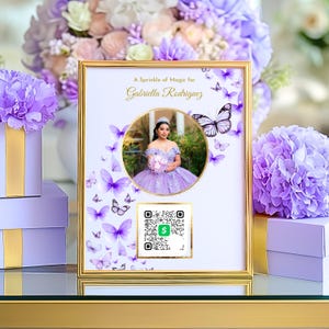 Puede incluir: Marco dorado con foto de una joven con vestido lavanda. El marco incluye el texto "A Sprinkle of Magic for Gabriella Rodriguez" y motivos de mariposas. Se ve un código QR.
