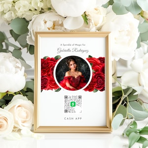 May include: A white framed sign with red roses and a photo of a girl in a red dress. The sign says "A Sprinkle of Magic for Gabriella Rodriguez" and has a QR code with the text "CASH APP".