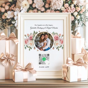 以下が含まれることがあります： 花柄で飾られた、カップルの結婚写真が額装されています。「Our happily ever after begins...」のテキストとGabriella Rodriguez & Rafael Moralesの名前がフレームに表示されています。Cash AppのQRコードも表示されています。