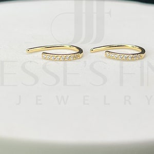 May include: A pair of gold hoop earrings with a row of small clear stones on each hoop.