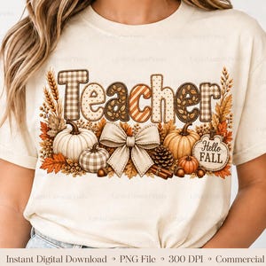 May include: A cream-colored t-shirt featuring a graphic with the word Teacher in patterned letters. The design includes white and orange pumpkins, a large beige bow, pinecones, wheat stalks, autumn leaves, and a sign that says Hello Fall.