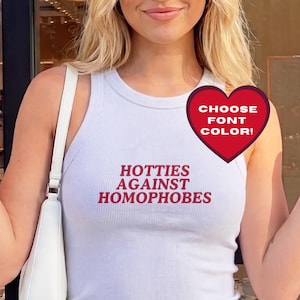 Puede incluir: Camiseta sin mangas blanca acanalada con el texto "Hotties Against Homophobes" en rojo. También se ve un corazón rojo con el texto "Choose Font Color!". La camiseta se combina con unos vaqueros azules.