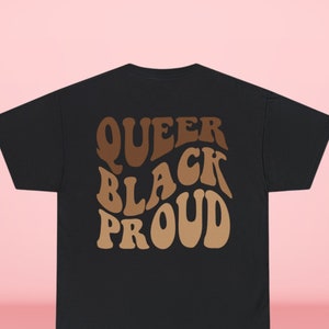 May include: Black t-shirt with the text "Queer Black Proud" in brown lettering with a gradient effect.
