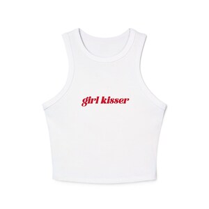 May include: White crop top with a scoop neck and the red text "girl kisser" printed across the front. The top is sleeveless and made of a soft, likely cotton material.