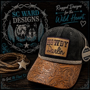 May include: A black baseball cap with a tan leather-look brim featuring an embossed floral pattern. The front panel displays a rectangular patch with the embroidered text Howdy Darlin in brown. A thin rhinestone band separates the crown and brim.