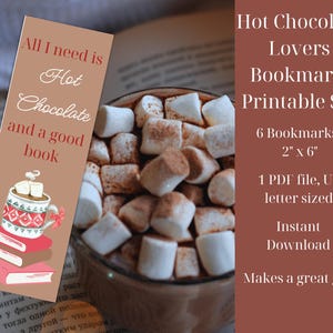 Op de afbeelding: Een printbare set van zes bladwijzers van 5x15 cm met een bruine mok met warme chocolademelk en marshmallows, en de tekst "Alles wat ik nodig heb is warme chocolademelk en een goed boek".