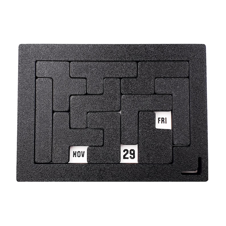 Op de afbeelding: Zwart puzzelbord met een witte kalenderdatum van 29 november en de dag van de week, vrijdag, zichtbaar.