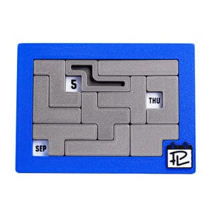 Op de afbeelding: Een blauwe plastic kalenderpuzzel met een grijs doolhof. Het doolhof heeft het nummer "5" en de woorden "SEP" en "THU" erin. De puzzel heeft een kalenderpictogram met het nummer "12" erop.