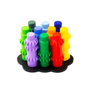 May include: A collection of colorful, cylindrical game pieces in various colors, including green, purple, red, and yellow. Each piece has a ruffled design and sits on a black, cloud-shaped base. The pieces are arranged in a circular pattern.