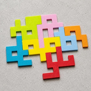 Könnte beinhalten: Eine Ansammlung ineinandergreifender geometrischer Puzzleteile in leuchtenden Farben wie Limettengrün, Pink, Orange, Gelb, Hellblau, Dunkelblau und Rot. Jedes Teil hat eine eigene Form mit quadratischen Aussparungen und ist zu einem Cluster angeordnet.