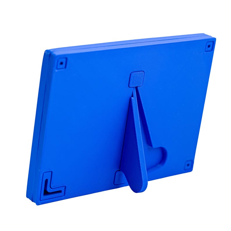 Op de afbeelding: Een blauwe plastic fotolijst met een ingebouwde standaard. De standaard klapt uit om de lijst rechtop te zetten.