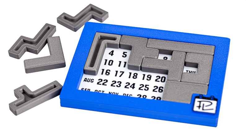 Op de afbeelding: Een blauwe kalenderpuzzel met grijze puzzelstukken. De puzzelstukken zijn L-vormig en passen in het kalenderrooster. De kalender toont de maanden augustus tot en met december.