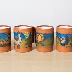 May include: Four ceramic mugs with hand-painted designs. Each mug features a different animal: a cat, a llama, a bird, and a fish. The mugs have a brown exterior, white interior, and a rectangular handle.