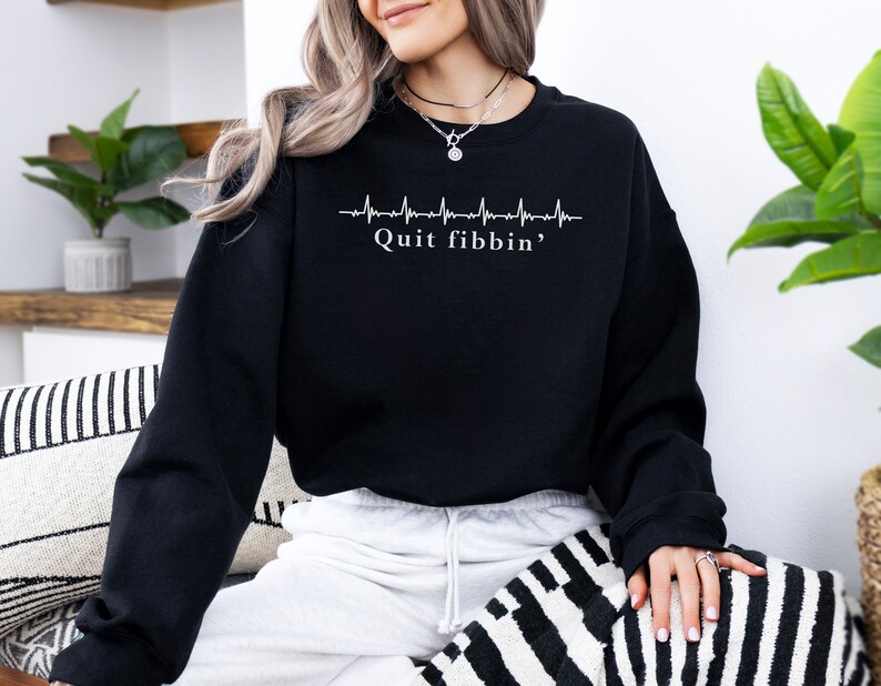 a woman sitting on a couch wearing a black sweatshirt