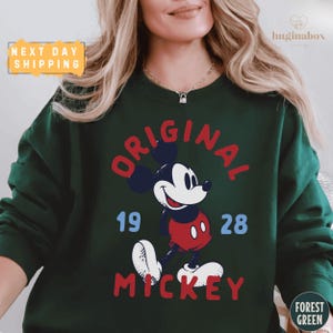 A woman wearing a green sweatshirt with a graphic of Mickey Mouse printed on it.