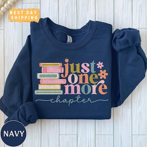 May include: Navy blue sweatshirt featuring a stack of colourful books and the text "just one more chapter".
