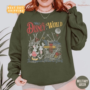 A woman wearing a green sweatshirt with a graphic design featuring Disney characters and the text "Disney World".
