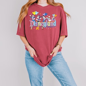 a woman wearing a disneyland shirt and jeans