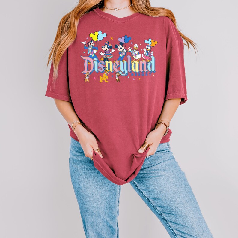 a woman wearing a disneyland shirt and jeans