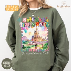 A woman wearing a green sweatshirt with a colorful graphic of Disney World and the text "Walt Disney World" printed on it.