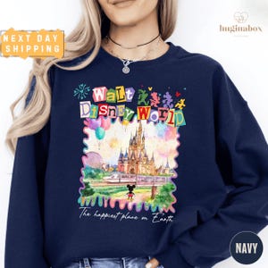 A woman wearing a navy blue sweatshirt with a colorful graphic of Walt Disney World and the text "The happiest place on Earth" printed on it.
