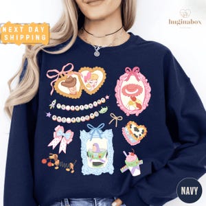 A woman wearing a navy blue sweatshirt with various cartoon-style illustrations and text on it.