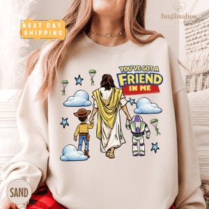 A woman wearing a white sweatshirt with a cartoon illustration of a person holding hands with a child and a character from the Toy Story franchise.